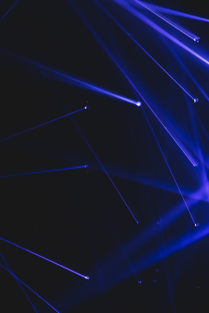 Chaotic abundance of blue beams of modern equipment shining in dark room of contemporary hall during light performance with glowing rays